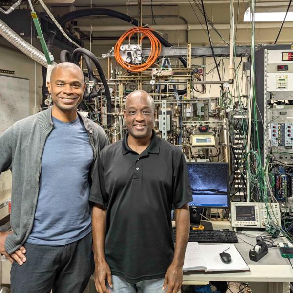 Fred Lacy and Kolo Wamba stand in front experimental equipment.